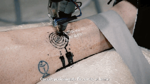 Photo of a robot making a tattoo
